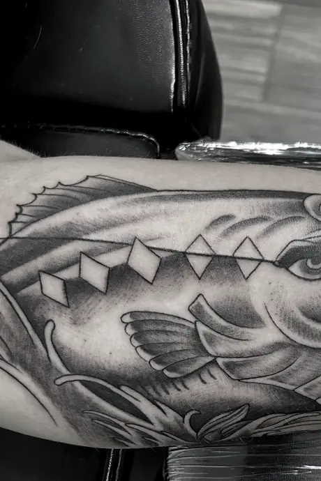 Black and grey bass across a forearm, worked in grey wash with the scales picked out in fine detail.