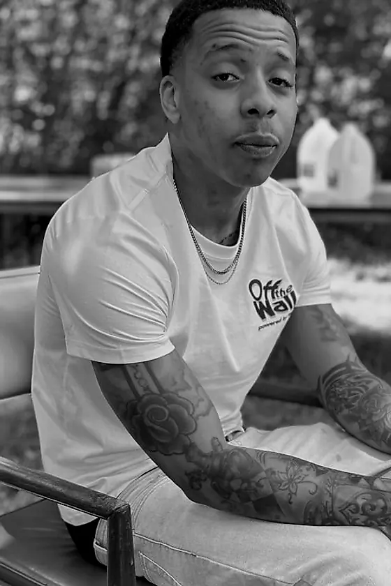 Cortez Thompson seated outdoors in a white tee, both forearms fully sleeved.